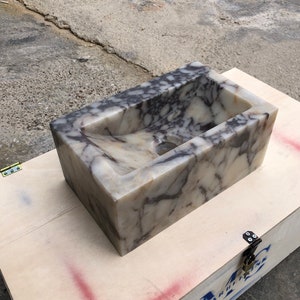 Calacatta Viola marble wall-mount sink with stunning natural veining. Handcrafted floating stone basin with no overflow, single faucet hole. Perfect for luxury bathrooms, interior designers, boutique hotels, and modern renovations. Ideal as a vessel sink, bar sink, or designer washbasin. Unique Italian marble sink for minimalist, high-end bathrooms. Trending marble bathroom decor, handcrafted stone sink.