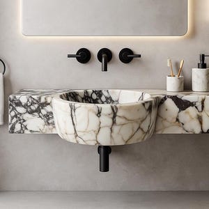 Luxurious wall-mounted Calacatta marble sink carved from a single block. Featuring 3 faucet holes, fluted front design, and floating vanity look. Ideal for modern, minimalist bathrooms. Custom sizes available. Handmade from natural Italian stone. Bathroom sink, marble vanity, stone basin, designer sink, fluted marble, wall mount sink, handmade sink, rectangular sink, luxury bathroom decor.