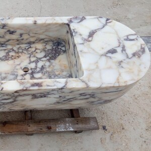 Suspended marble sink made from rare Calacatta Viola marble, floating vanity basin carved by master artisans, luxury architectural statement sink designed for high end bathrooms, sculptural stone sink suspended with ceiling chains creating a dramatic floating illusion, custom luxury marble sink perfect for designer interiors and iconic architectural spaces