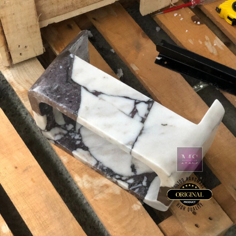 Rear view of the wall-mounted marble sink showing its carved mounting profile, thick construction and continuous natural veining.