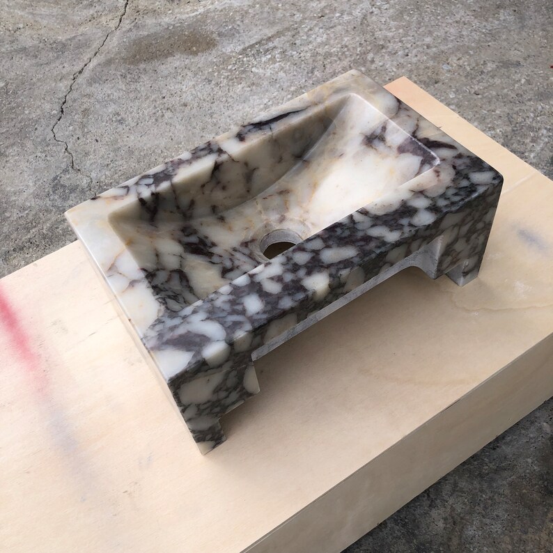 Calacatta Viola marble wall-mount sink with stunning natural veining. Handcrafted floating stone basin with no overflow, single faucet hole. Perfect for luxury bathrooms, interior designers, boutique hotels, and modern renovations. Ideal as a vessel sink, bar sink, or designer washbasin. Unique Italian marble sink for minimalist, high-end bathrooms. Trending marble bathroom decor, handcrafted stone sink.
