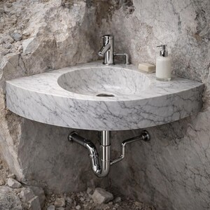 May include: A marble corner sink with a chrome faucet and drainpipe. The sink is white with gray veining and is mounted in a rough-hewn stone wall. A soap dish and soap dispenser are on the sink's surface.