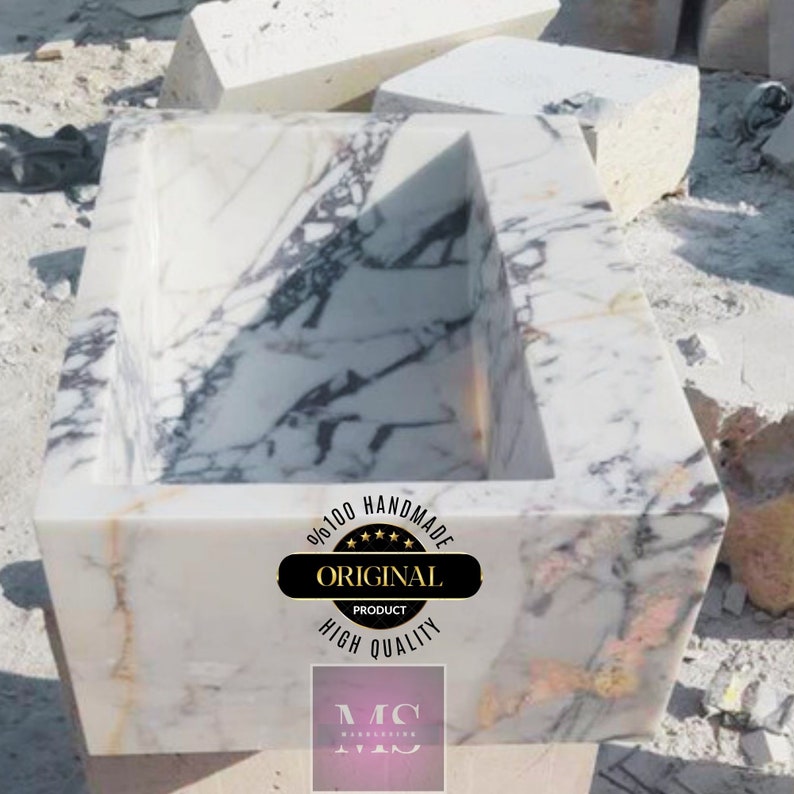 May include: A white marble sink with a rectangular shape and a unique design. The sink is handmade and features a label that says "100% Handmade Original Product High Quality".
