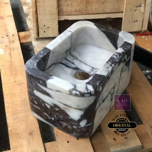 Side-angle view of the Calacatta Viola marble basin showing the deep carved bowl, polished interior and natural stone pattern.