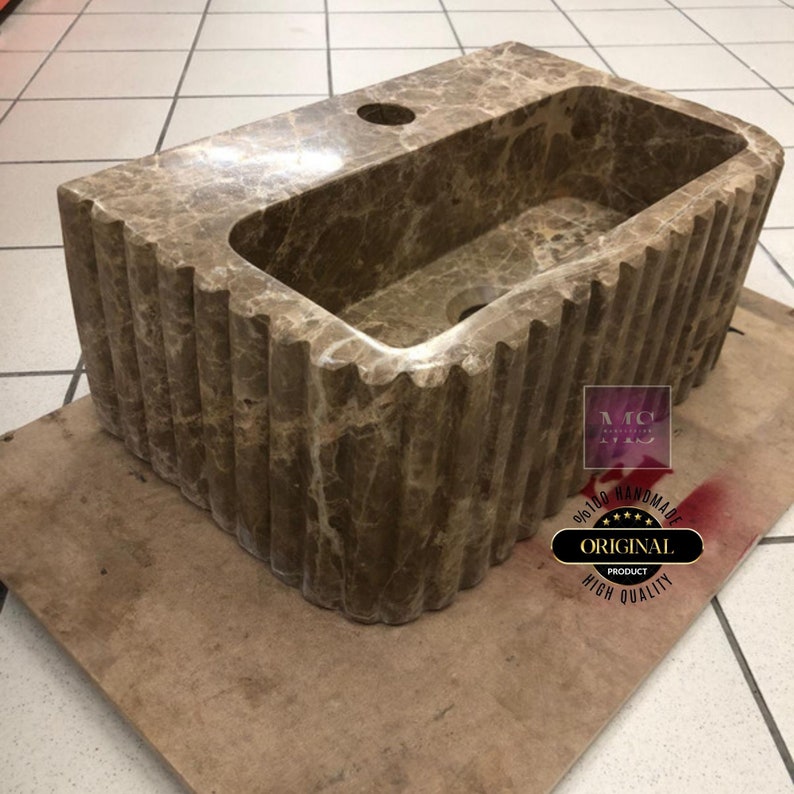 May include: A brown marble sink with a rippled edge. The sink is handmade and has a high quality finish.
