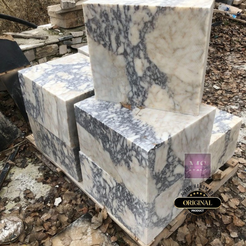 Puede incluir: Cuatro grandes bloques de m&aacute;rmol blanco con vetas grises. Los bloques est&aacute;n apilados uno encima del otro. El bloque superior tiene el texto "100% HANDMADE ORIGINAL PRODUCT" impreso en &eacute;l.
