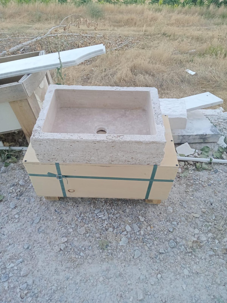Luxury handcrafted natural travertine wall mounted bathroom sink installed in a premium modern bathroom with chrome fixtures.