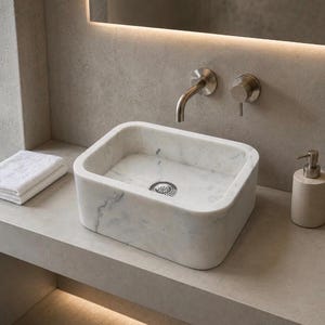 Handmade Carrara marble vessel sink styled on a modern bathroom vanity with white stone and natural grey veins