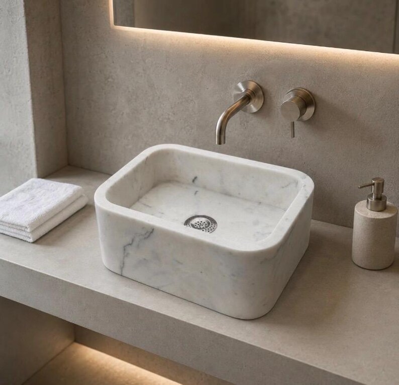 Handmade Carrara marble vessel sink styled on a modern bathroom vanity with white stone and natural grey veins