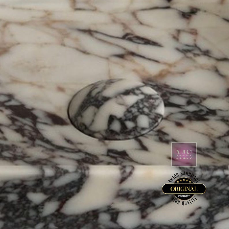 Puede incluir: Primer plano de un lavabo de m&aacute;rmol blanco con una tapa de desag&uuml;e redonda de m&aacute;rmol blanco. El lavabo tiene un patr&oacute;n de vetas grises y moradas en espiral. El texto "100% HANDMADE ORIGINAL PRODUCT HIGH QUALITY" es visible en la esquina inferior derecha de la imagen.