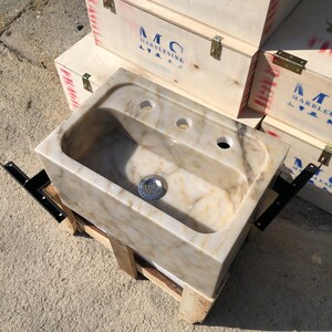 Close overhead view of the Calacatta Viola marble sink bowl, highlighting the polished cream stone, gold and grey natural veining, centered drain, three faucet holes and rounded inner corners.