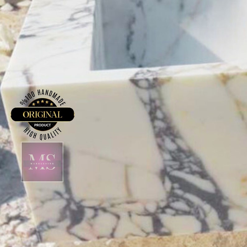 May include: A white marble sink with gray and purple veining. The sink is handmade and has a label that says "100% Handmade Original Product High Quality".
