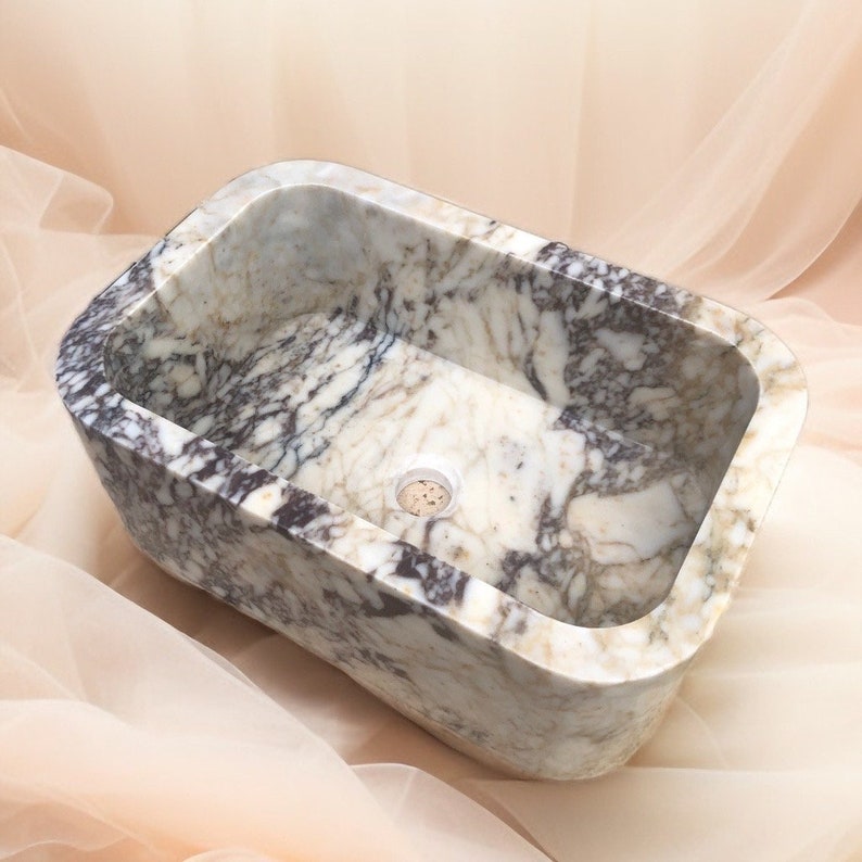 Luxury handcrafted Calacatta Viola marble floating wall mounted bathroom sink with fluted front in a premium designer bathroom.