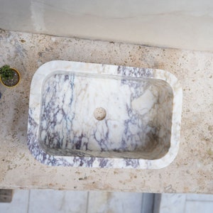 Luxury handcrafted Calacatta Viola marble floating wall mounted bathroom sink with fluted front in a premium designer bathroom.