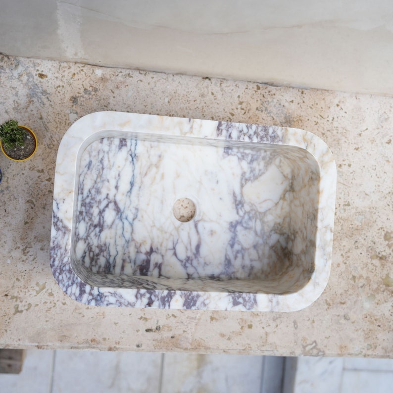 Luxury handcrafted Calacatta Viola marble floating wall mounted bathroom sink with fluted front in a premium designer bathroom.