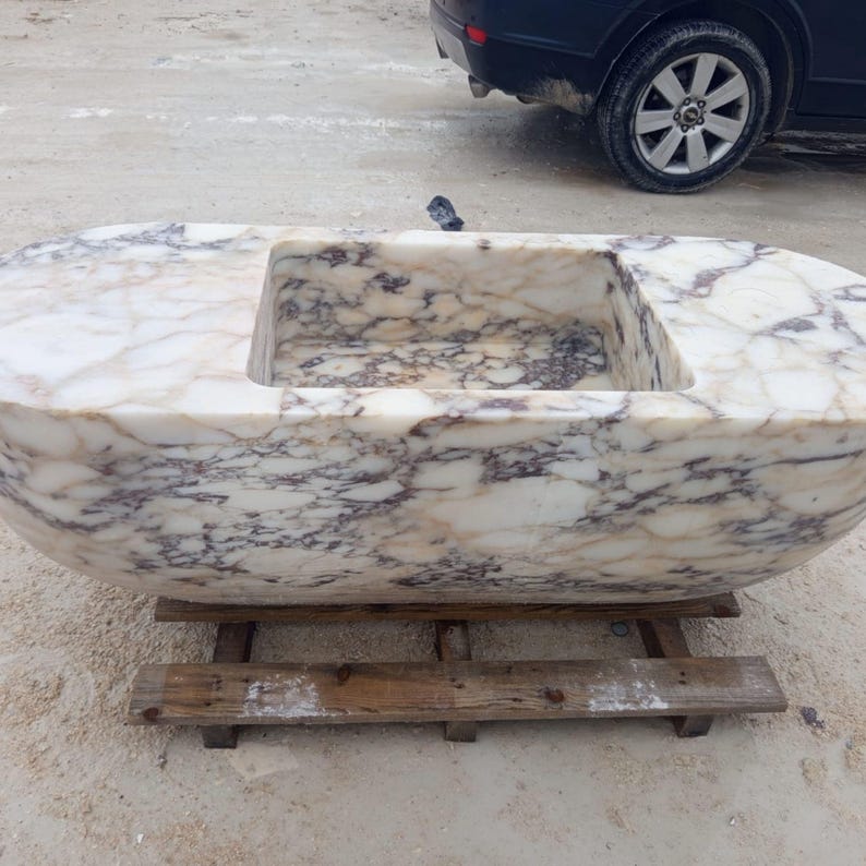 Calacatta Viola suspended marble sink, luxury floating vanity sink hand carved from a 2 ton marble block, rare sculptural bathroom basin designed for luxury villas, penthouses and designer interiors, architectural statement sink suspended with steel chains creating a dramatic floating illusion, premium handmade marble sink crafted by MarbleSinkCo masters, collectible luxury bathroom centerpiece shipped worldwide with DHL Express