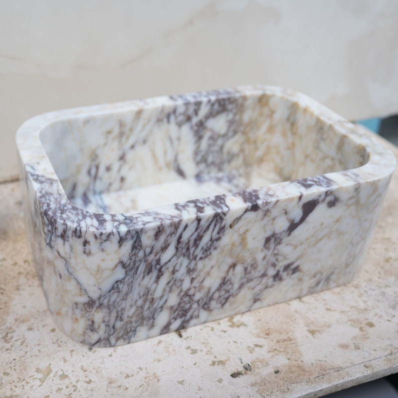 Luxury handcrafted Calacatta Viola marble floating wall mounted bathroom sink with fluted front in a premium designer bathroom.