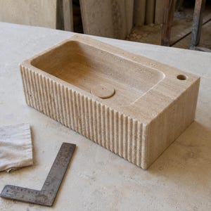 Hand-carved Light Travertine bathroom sink photographed during workshop quality control