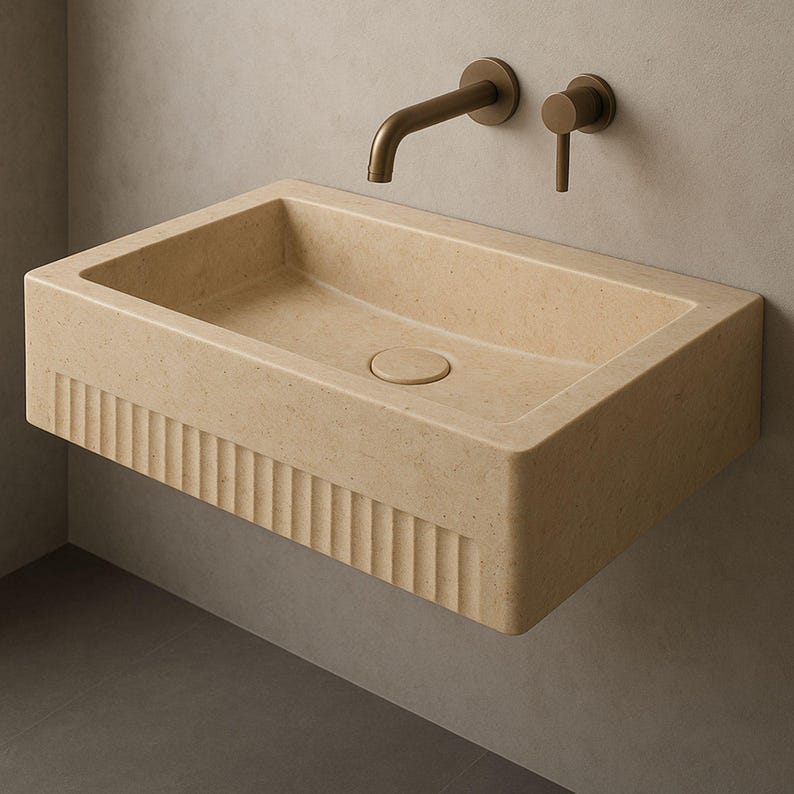 Handmade travertine wall-mounted sink with fluted front and matte finish. Custom sizes available. Ideal for luxury bathrooms, hotels, interior designers, and modern spa spaces. Each basin is carved from solid stone. Ships globally in a wooden crate via DHL Express. Natural veining varies uniquely in each piece.Perfect for minimalist,rustic,and architectural interiors, travertine wall-mounted sink,fluted front, solid stone, custom sizes,interior designers, modern spa, luxury bathrooms, minimalist