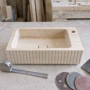 Handmade travertine sink undergoing final finishing and inspection in a natural stone workshop
