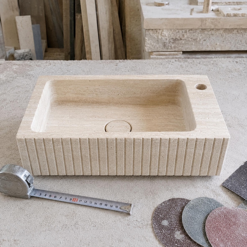 Handmade travertine sink undergoing final finishing and inspection in a natural stone workshop
