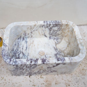 Luxury handcrafted Calacatta Viola marble floating wall mounted bathroom sink with fluted front in a premium designer bathroom.