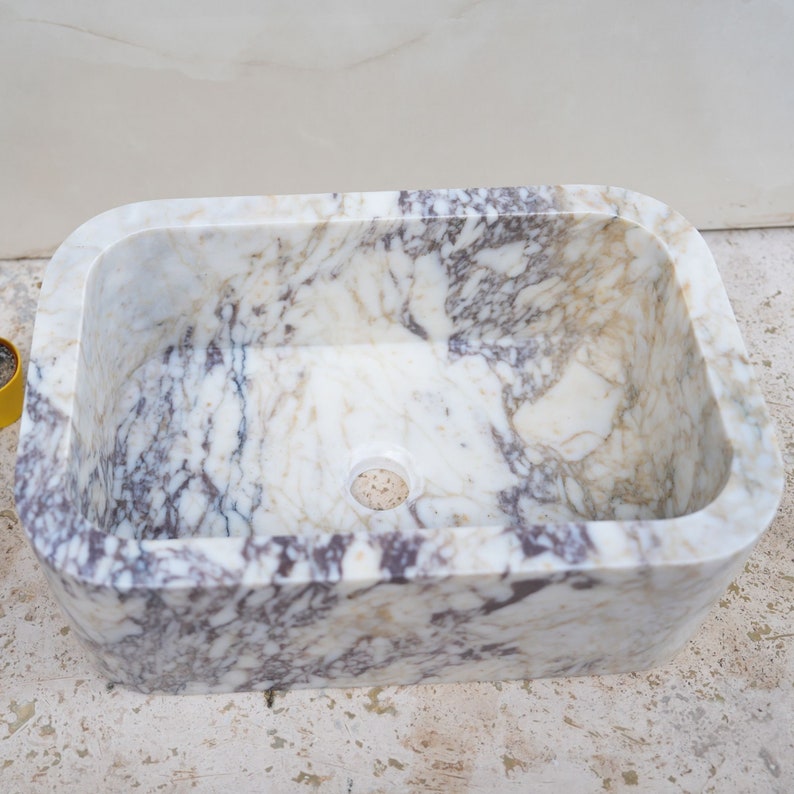 Luxury handcrafted Calacatta Viola marble floating wall mounted bathroom sink with fluted front in a premium designer bathroom.
