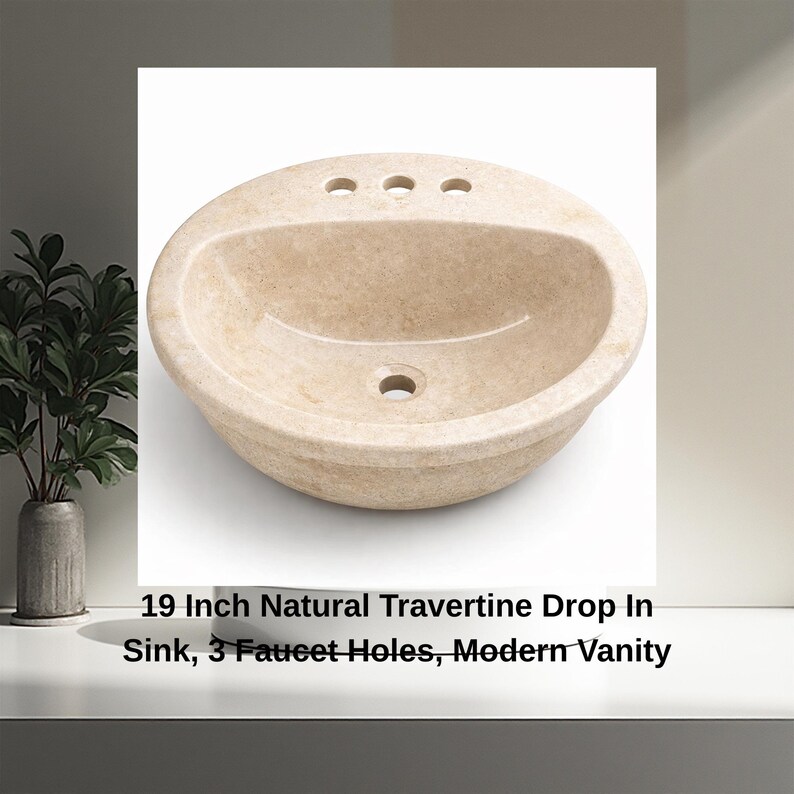 May include: A natural travertine drop-in sink with three faucet holes. The oval-shaped sink is 19 inches in diameter and has a light beige color. The sink is designed for a modern vanity.