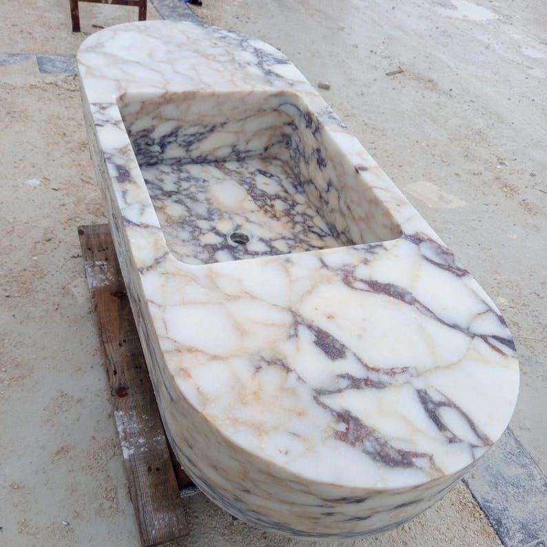 Rare Calacatta Viola marble sink designed as a suspended floating vanity sink, hand carved luxury stone basin created from a massive marble block, architectural statement bathroom sink perfect for modern villas, penthouses and luxury interiors, sculptural designer bathroom basin suspended with steel chains, exclusive handmade marble sink crafted by MarbleSinkCo artisans