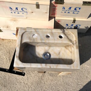 Direct overhead view of a rectangular Calacatta Viola marble bathroom sink with a deep rounded bowl, centered drain, three faucet holes and natural cream, gold and grey stone veining.