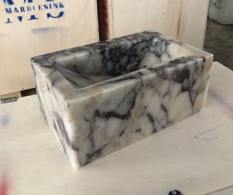 Calacatta Viola marble wall-mount sink with stunning natural veining. Handcrafted floating stone basin with no overflow, single faucet hole. Perfect for luxury bathrooms, interior designers, boutique hotels, and modern renovations. Ideal as a vessel sink, bar sink, or designer washbasin. Unique Italian marble sink for minimalist, high-end bathrooms. Trending marble bathroom decor, handcrafted stone sink.