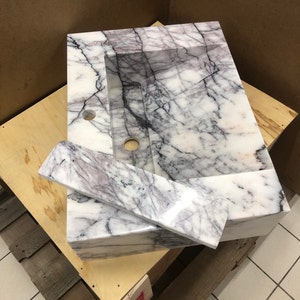 natural-stone-sink-collection.jpg MarbleSinkCo natural stone collection with labeled Carrara, Calacatta, Lilac, Travertine and Nero Marquina samples.