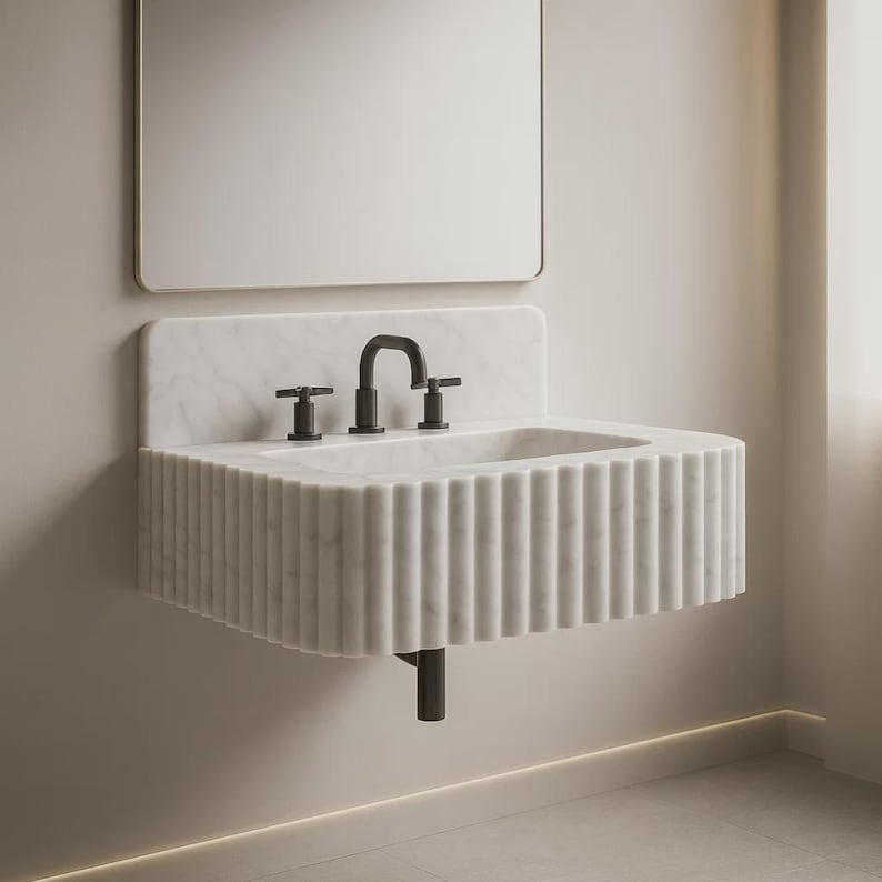 Carrara marble bathroom sink with premium natural stone veining, handcrafted from solid Carrara marble with a 6-inch rounded backsplash. Wall-mounted or countertop installation, modern minimalist luxury bathroom design. High-end 3-hole faucet installed, polished surface, durable natural stone craftsmanship. Perfect for luxury interior design projects, small bathrooms, powder rooms, hotels, and modern home renovations. Premium quality, handcrafted marble vanity sink shipped worldwide via DHL