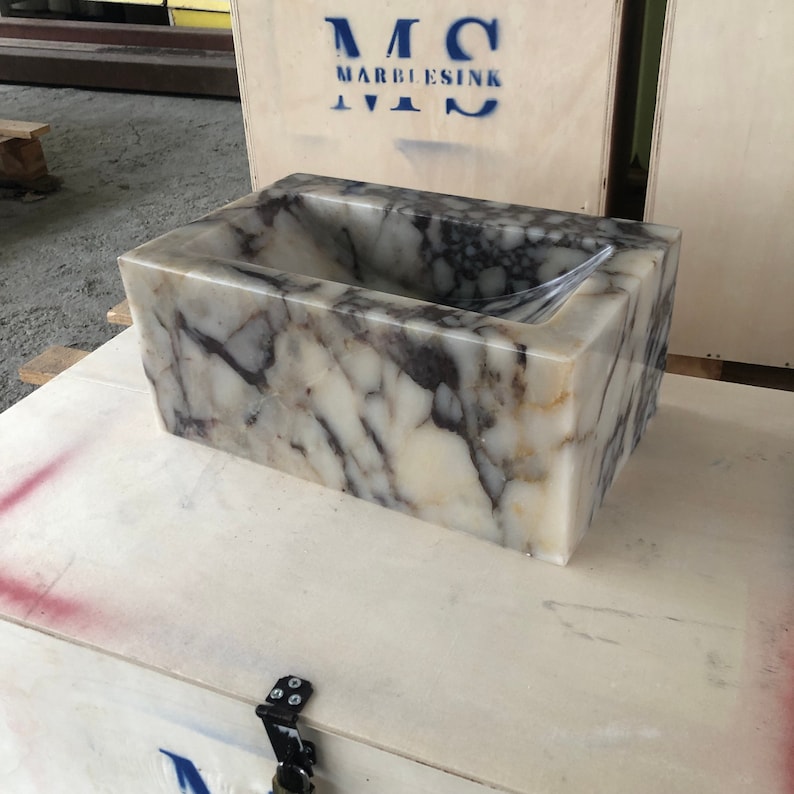 Calacatta Viola marble wall-mount sink with stunning natural veining. Handcrafted floating stone basin with no overflow, single faucet hole. Perfect for luxury bathrooms, interior designers, boutique hotels, and modern renovations. Ideal as a vessel sink, bar sink, or designer washbasin. Unique Italian marble sink for minimalist, high-end bathrooms. Trending marble bathroom decor, handcrafted stone sink.