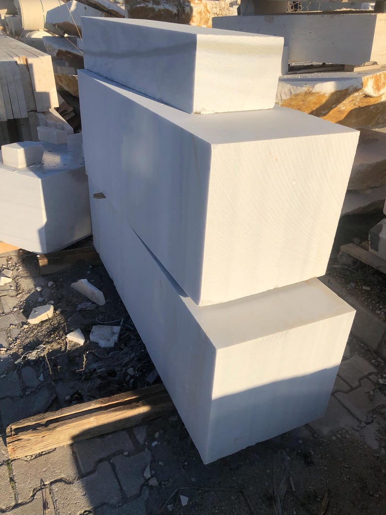 May include: Three white marble blocks stacked on top of each other. The blocks are rectangular and have a smooth, polished surface.