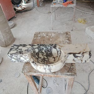 Luxurious wall-mounted Calacatta marble sink carved from a single block. Featuring 3 faucet holes, fluted front design, and floating vanity look. Ideal for modern, minimalist bathrooms. Custom sizes available. Handmade from natural Italian stone. Bathroom sink, marble vanity, stone basin, designer sink, fluted marble, wall mount sink, handmade sink, rectangular sink, luxury bathroom decor.