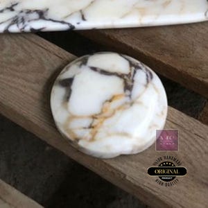 Puede incluir: Un posavasos redondo de m&aacute;rmol blanco con vetas marrones y doradas. El posavasos es liso y pulido. Est&aacute; hecho a mano y tiene un acabado de alta calidad.