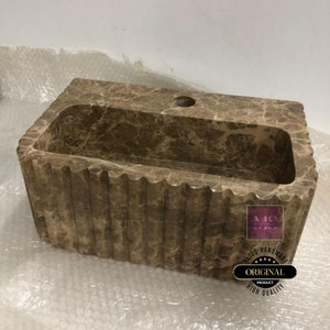 May include: A brown marble bathroom sink with a rectangular shape and a wavy edge. The sink has a single hole for a faucet and is made of natural stone. The sink is handmade and has a high quality finish.