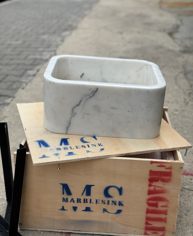Straight front view of a solid Carrara White marble bathroom basin highlighting the thick polished apron, softly rounded corners and distinctive grey marble vein.