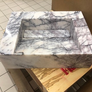 carrara-white-marble-veining-closeup.jpg Close-up of genuine Carrara White marble showing the polished surface, natural gray veining and small mineral details.