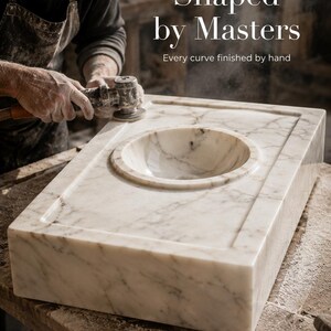 Raw Calacatta Gold marble block extracted from a quarry, showing natural white stone with gray and golden veining before becoming a handmade marble sink