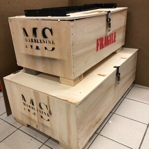 Reinforced wooden shipping crates prepared for insured worldwide delivery of handmade Carrara marble sinks and heavy-duty wall mounting brackets.