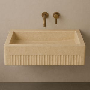 Handmade travertine wall-mounted sink with fluted front and matte finish. Custom sizes available. Ideal for luxury bathrooms, hotels, interior designers, and modern spa spaces. Each basin is carved from solid stone. Ships globally in a wooden crate via DHL Express. Natural veining varies uniquely in each piece.Perfect for minimalist,rustic,and architectural interiors, travertine wall-mounted sink,fluted front, solid stone, custom sizes,interior designers, modern spa, luxury bathrooms, minimalist