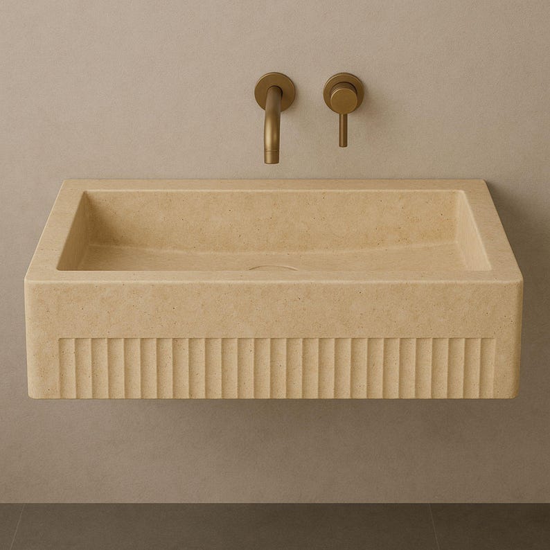 Handmade travertine wall-mounted sink with fluted front and matte finish. Custom sizes available. Ideal for luxury bathrooms, hotels, interior designers, and modern spa spaces. Each basin is carved from solid stone. Ships globally in a wooden crate via DHL Express. Natural veining varies uniquely in each piece.Perfect for minimalist,rustic,and architectural interiors, travertine wall-mounted sink,fluted front, solid stone, custom sizes,interior designers, modern spa, luxury bathrooms, minimalist