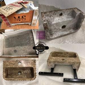 May include: A brown marble sink with a rectangular basin and a decorative edge. The sink is mounted on a black metal stand. The sink is packaged in a wooden crate with the text "MC MARBLESINK NAT" printed on the side.