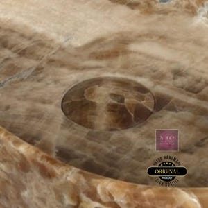 Puede incluir: Primer plano de un lavabo de &oacute;nix marr&oacute;n y beige con un agujero de drenaje. El lavabo est&aacute; hecho a mano y tiene un acabado de alta calidad.