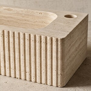 Close-up of natural Light Travertine pores and handcrafted vertical fluted sink exterior