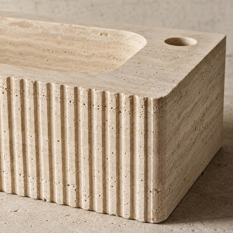 Close-up of natural Light Travertine pores and handcrafted vertical fluted sink exterior