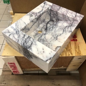 marblesinkco-carrara-sink-workshop.jpg Carrara marble sink resting on a workshop table during final inspection at the MarbleSinkCo stone atelier in Türkiye.