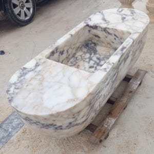 Collectible architectural marble sink made from rare Calacatta Viola marble, suspended luxury bathroom basin carved by hand from a massive stone block, floating vanity sink with dramatic sculptural presence designed for luxury villas and penthouses, premium handmade marble sink by MarbleSinkCo masters shipped worldwide with DHL Express